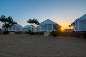 a group of houses on the beach at sunset at Rajwada Desert Camp in Jaisalmer