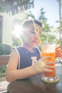 a young boy sitting at a table with a drink at V&T Hotel Phu Quoc - 3 minutes to Beach in Phú Quốc