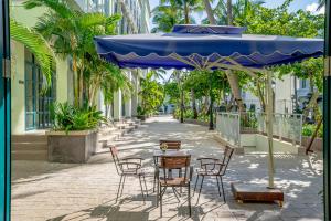 a table with chairs and a blue umbrella on a street at V&T Hotel Phu Quoc - 3 minutes to Beach in Phú Quốc