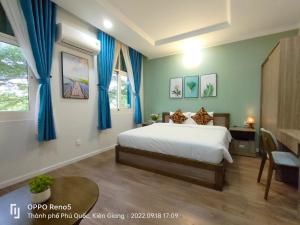 a bedroom with a bed with blue curtains and a table at V&T Hotel in Phú Quốc