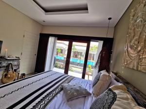ein Schlafzimmer mit einem Bett und einem großen Fenster in der Unterkunft Kubu Garden Suites & Villas Nusa Dua in Nusa Dua