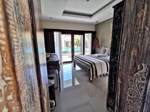 a bedroom with a bed and a dresser and a mirror at Kubu Garden Suites & Villas Nusa Dua in Nusa Dua