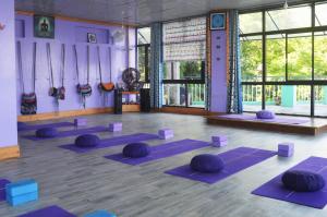 a yoga class with purple mats in a room with windows at Yoga House in McLeod Ganj