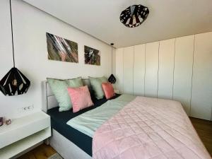 1 dormitorio con 1 cama con almohadas rosas y verdes en Apartman Ana, en Daruvar