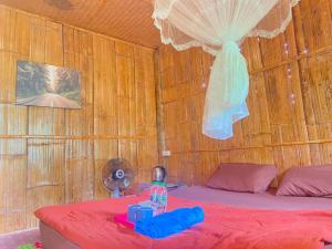 a bedroom with a bed with a red bedspread at ลุงนะ โฮมสเตย์ ปางอุ๋ง แม่ฮ่องสอน in Ban Huai Makhuea Som