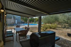 a patio with a television and a table and a pool at Apartment Villa Oliva in Gostinjac
