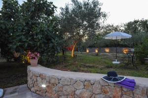 a hat sitting on a stone wall with an umbrella at Apartment Villa Oliva in Gostinjac