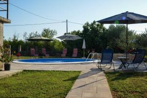 a swimming pool with two chairs and umbrellas at Apartment Villa Oliva in Gostinjac