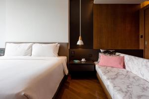 a bedroom with a large bed and a couch at Volve Hotel Bangkok in Bangkok