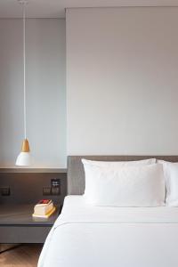 a bedroom with a white bed and a table with books at Volve Hotel Bangkok in Bangkok