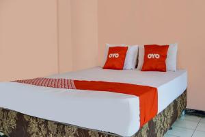 Una cama con dos almohadas rojas encima. en SPOT ON 91797 Mutiara Guest House, en Karawang