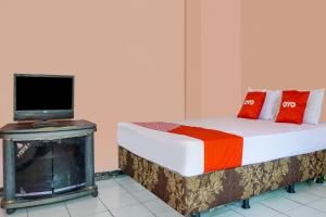 a bedroom with a bed and a tv on a fireplace at SPOT ON 91797 Mutiara Guest House in Karawang