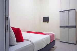 a bedroom with a bed with red pillows and a tv at SUPER OYO Capital O 91790 S1 Residence in Tangerang