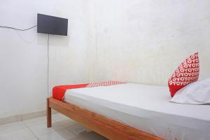 Schlafzimmer mit einem Bett und einem TV an der Wand in der Unterkunft SPOT ON 91786 Kilana Homestay in Makassar
