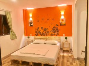sypialnia z łóżkiem z pomarańczową ścianą w obiekcie Như Mây Homestay w Duong Dong