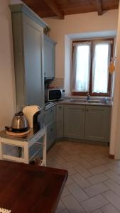 a kitchen with green cabinets and a table in a room at CASA MAIRA IN CENTRO A SATURNIA in Saturnia