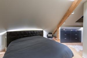 ein Schlafzimmer mit einem großen schwarzen Bett im Dachgeschoss in der Unterkunft Mairnaige, luxueux appartement avec sauna in Gérardmer