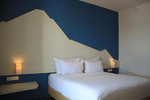 - une chambre avec un lit blanc et un mur bleu dans l'établissement Bromo Park Hotel Probolinggo, à Probolinggo