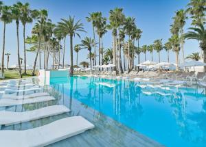 a pool with palm trees and white lounge chairs at Leonardo Plaza Cypria Maris Beach Hotel & Spa in Paphos