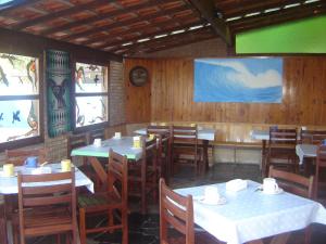 una sala da pranzo con tavoli, sedie e finestre di Waldhaus - A Pousada do Remo a Peruíbe