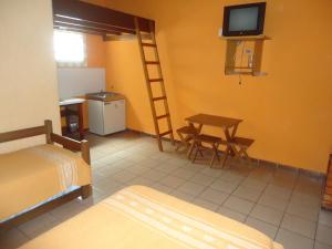 una camera da letto con un letto, una scrivania e una televisione di Waldhaus - A Pousada do Remo a Peruíbe