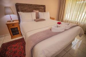 - une chambre dotée d'un grand lit blanc avec une fleur dans l'établissement Palm villa, à Harare