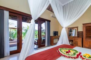 Schlafzimmer mit einem Bett mit weißen Vorhängen in der Unterkunft Santris Villas by Pramana Villas in Ubud