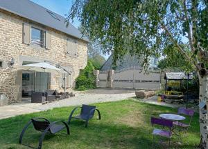 einen Garten mit Stühlen, einem Tisch und einem Sonnenschirm in der Unterkunft Au Mont & Merveilles in Sartilly