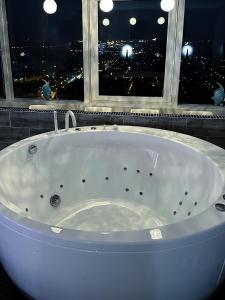 a bath tub in a bathroom with a view of a city at sky DREAM jacuzzi sauna 33 FLOOR in Klaipėda