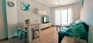 uma sala de estar com um sofá azul e uma mesa em Apartamento planta baja Residencial Aquamarina by costablancarent em Denia