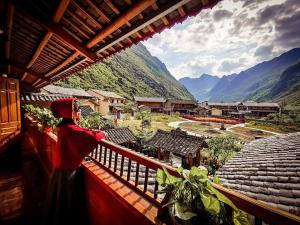 a woman standing on a balcony looking at the mountains at MeoVac Ethnic Homes in Mèo Vạc