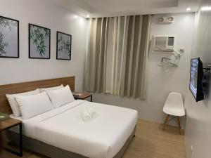 a hotel room with a white bed and a television at Bambu Suites in Puerto Princesa City