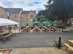 a parking lot with picnic tables and green umbrellas at Hen House in Cannock