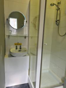 a bathroom with a sink and a shower with a mirror at Hen House in Cannock