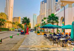 chodnik ze stołami, krzesłami i parasolami przy ulicy miejskiej w obiekcie Murjan Suites Waterfront The Walk Jumeirah Beach Residence w Dubaju