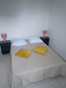 a white bed with two yellow pillows and two lamps at Superbe appartement avec parking gratuit in Sainte-Anne
