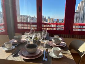 una mesa con platos y copas de vino y vistas a la ciudad en Anna’s apartment, en Benidorm