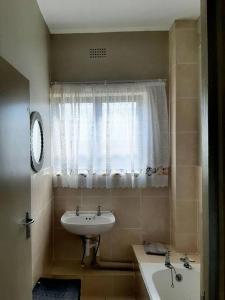 a bathroom with a sink and a tub and a window at La Corsica Beach House Breakaway in Margate
