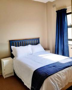a bedroom with a large bed with a blue curtain at La Corsica Beach House Breakaway in Margate