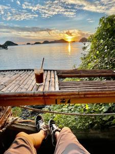 a person sitting on a dock with a drink on a table at THU HA SEA VIEW Hotel in Cat Ba