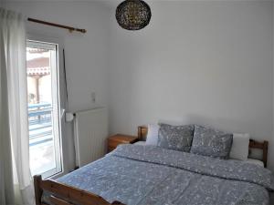 a bed with a blue comforter in a bedroom with a window at Vassilikos Apartment in Flogita