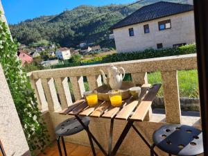 una mesa en un balcón con 2 vasos de zumo de naranja en A Veiga Grande, en Pontevedra
