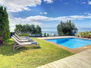 a group of lounge chairs next to a swimming pool at Unmei by LovelyStay in Caniço