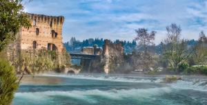 a castle next to a river with a bridge at Il Borghetto Vacanze nei Mulini in Valeggio sul Mincio