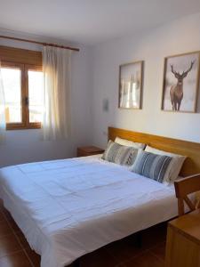 1 dormitorio con 1 cama blanca grande y un ciervo en la pared en Apartamento Superesquí 251 en La Molina Alp