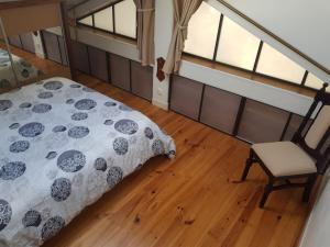 ein Schlafzimmer mit einem Bett und einem Stuhl sowie zwei Fenstern in der Unterkunft spacieuse maison de ville avec espace détente in Rezé