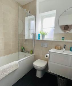 霍爾特的住宿－NEW! Beautiful contemporary property in Holt, Norfolk，浴室配有卫生间、浴缸和水槽。