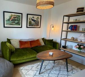NEW! Beautiful contemporary property in Holt, Norfolk في هولت: غرفة معيشة مع أريكة خضراء وطاولة