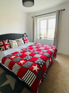 Una cama en un dormitorio con una manta roja y blanca en NEW! Beautiful contemporary property in Holt, Norfolk en Holt