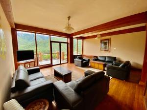a living room with leather furniture and a large window at Taktsang Village Resort in Paro